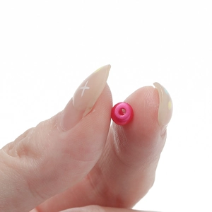 Vista macro di una perla distanziatrice in acrilico rosa perlato 3-5mm per bijoux DIY