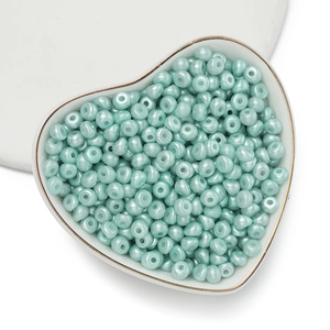 Dettaglio macro di perle in acrilico verde menta lucido in una ciotola a forma di cuore