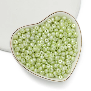 Dettaglio di perle acriliche irregolari verde chiaro perlescenti in un vassoio a cuore