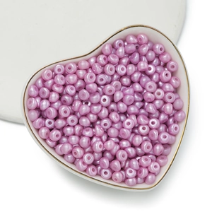 Vista macro di perle acriliche lavanda in ciotola a cuore per creazione di gioielli