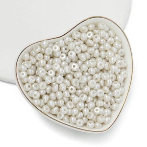Dettaglio macro di perle in acrilico bianco crema a goccia in un vassoio di cuore