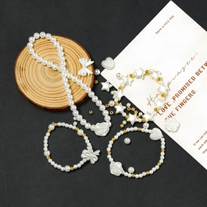 Flat lay of DIY faux pearl bead kit with floral and heart charms on black background