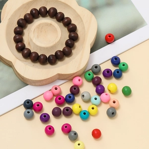 Gros plan de perles en bois colorées et bracelet marron sur un plateau en fleurs