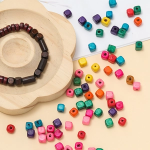 Close-up of colorful square wooden beads and a brown beaded bracelet on a wood tray