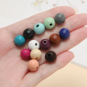 Main tenant des perles en bois mat colorées avec trous centraux pour bijoux DIY