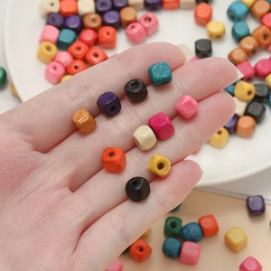 Macro view of colorful square wooden spacer beads held in hand for DIY jewelry making