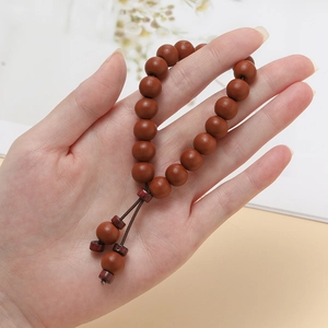 Détail d'un bracelet en perles de bois naturel marron porté au poignet avec des textures