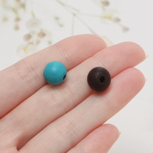 Détail de perles en bois mat bleu sarcelle et café pour création de bijoux DIY