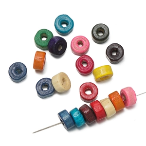 Macro shot of colorful flat cylindrical wooden beads strung on a metal needle for DIY jewelry