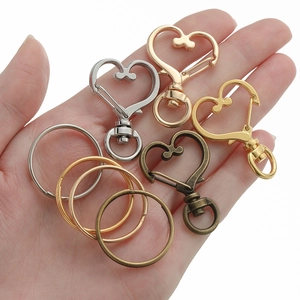 Dettaglio macro di moschettoni a cuore e anelli in quattro diverse finiture metalliche