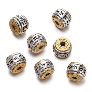 Macro detail of Tibetan silver and gold cylinder beads with Buddhist lotus and mantra engraving