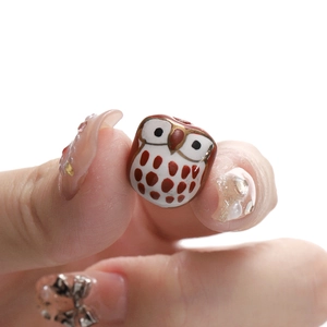 Macro shot of owl ceramic bead in red and white glaze with gold edges for DIY jewelry