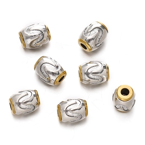 Macro view of silver alloy beads with wave patterns and gold-rimmed edges for jewelry