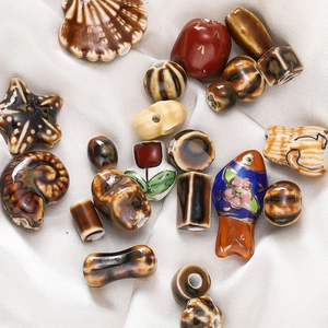 Close-up of ceramic beads in fish and star shapes on silk, for DIY jewelry making