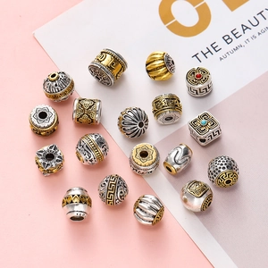 Detailed macro view of vintage gold and silver alloy beads with ethnic cloud patterns