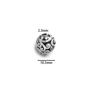 Macro view of a 10.5mm hollow vintage silver charm bead with ornate floral engravings