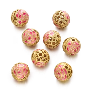 Close-up of hollow gold cloisonne beads with pink and red enamel floral patterns