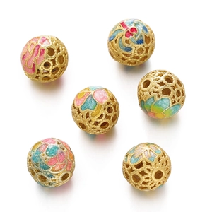 Detailed macro view of six gold hollow cloisonné enamel beads with floral filigree patterns