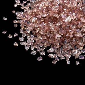 Vue macro de pierres en verre brisé or rose irisé avec éclat métallique sur fond noir