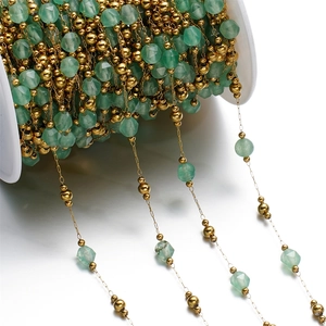 Detail of faceted light green stone beads with gold metal accents on a spool for DIY jewelry