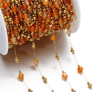 Macro shot of orange faceted gemstones and gold metal beads on a DIY jewelry chain