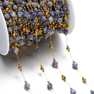 Macro shot of blue faceted natural stones and gold beads on a DIY jewelry chain roll