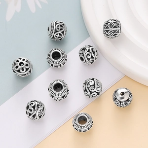 Macro view of vintage silver hollow beads with intricate floral and scroll engravings
