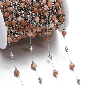 Macro shot of faceted orange natural stone beads and silver metal beads on a spool