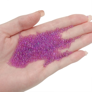Macro shot of tiny purple iridescent glass bubble beads for DIY nail art on palm