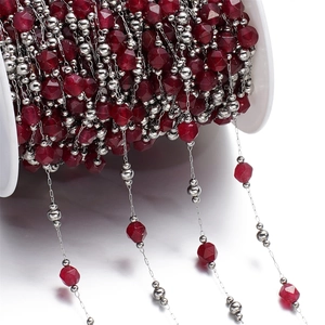 Macro detail of ruby red faceted stone beads and stainless steel DIY jewelry chain