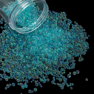 Macro of iridescent teal glass beads pouring from a container for DIY resin and nail art