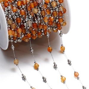 Macro view of orange faceted natural stone beads on a stainless steel DIY jewelry chain