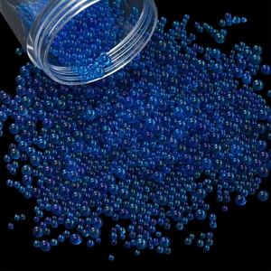Macro shot of iridescent blue and purple mini glass bubble beads pouring from a bottle