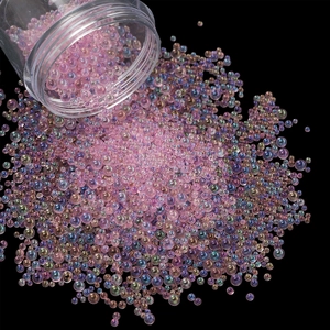 Close-up of pink iridescent glass micro beads spilling onto a black background for nail art