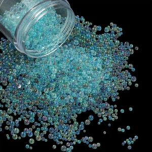 Close-up of iridescent blue bubble glass beads being poured from a clear plastic bottle