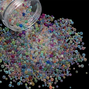 Macro shot of mixed size iridescent glass bubble beads pouring from a clear jar
