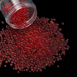 Detailed macro shot of red iridescent glass bubble beads pouring from a transparent jar