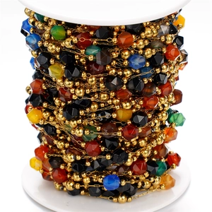 Detail of colorful faceted natural stone chain with gold beads on a white spool