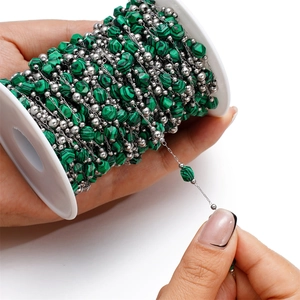 Detail of green malachite textured beads and silver beads on a chain for DIY jewelry
