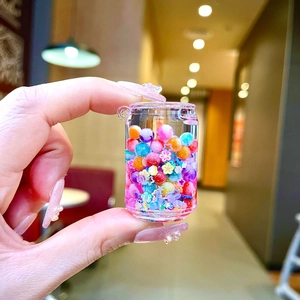 Gros plan d'une bouteille liquide de bonbons cœur avec perles et paillettes colorées