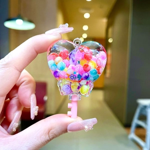 Vue détaillée du porte-clés bouteille en cœur avec perles colorées et nœud décoratif
