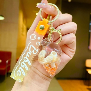 Detailed macro of a seashell liquid keychain with orange silicone strap and gold clasp