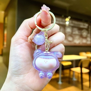 Macro detail of cute purple glitter acrylic keychain with golden metal ring and clasp