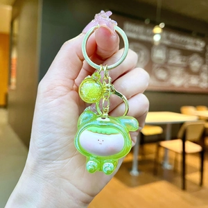 Detail of a green cartoon character keychain with acrylic bubble bead and gold metal clasp