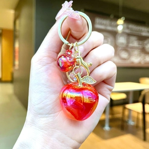 Detail showing red creative apple keychain with metallic finish and rhinestone leaf