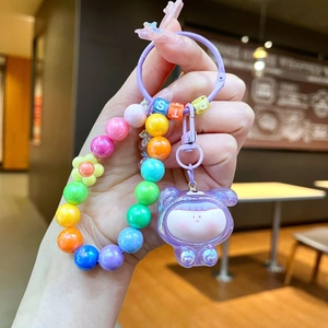 Detailed shot of a rainbow beaded phone charm with a cute purple cartoon bear pendant