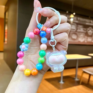 Handheld view of a colorful rainbow beaded keychain with translucent bear charm and beads