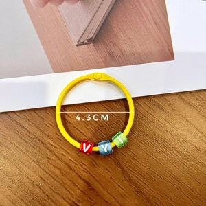 Close-up of 4.3cm yellow key ring with colorful alphabet beads V, Y, I on wood surface