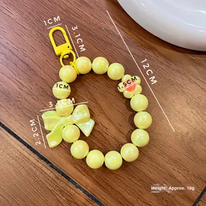 Detailed view of yellow beaded keychain wristlet with bow accessory and dimensions