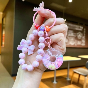 Close-up of pink beaded keychain with a donut pendant and bow accessory details